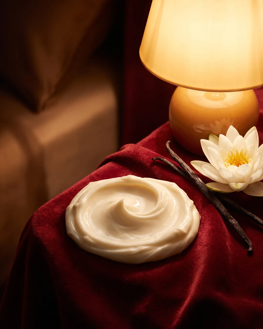 Night cream in an open palm by lamplight, beside mint and vanilla